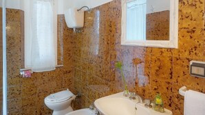 A bathroom with a sink, two toilets, a mirror, and a ceiling light fixture. - LA ROSA CANINA     . (Castiglione del Lago)