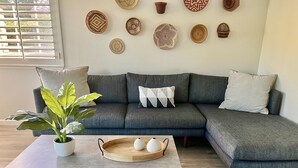 A modern living room with a grey sectional sofa, a coffee table, and decorative plates on the wall. - Palm Springs Private Home • Gated Cul‑de‑Sac • Pool, Spa & Backyard (Palm Springs)