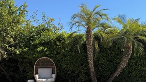 A swimming pool with blue tiles, a wicker chair, and a palm tree. - Palm Springs Private Home • Gated Cul‑de‑Sac • Pool, Spa & Backyard (Palm Springs)