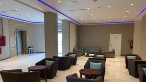 A modern lobby with seating areas, a reception desk, and a large window. - Hotel El Amine (Boumerdès)