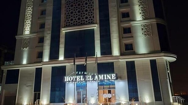 A multi-story hotel with a prominent sign reading "HOTEL EL AMINE" in both Arabic and English. - Hotel El Amine (Boumerdès)