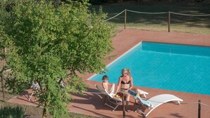 A swimming pool with two lounge chairs and a rope barrier. - IL GIAGGIOLO       . (Castiglione del Lago)