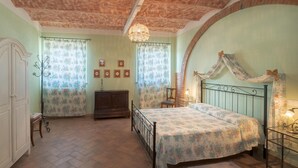 A bedroom with a bed, a dresser, a chair, and a desk. - IL GIAGGIOLO       . (Castiglione del Lago)