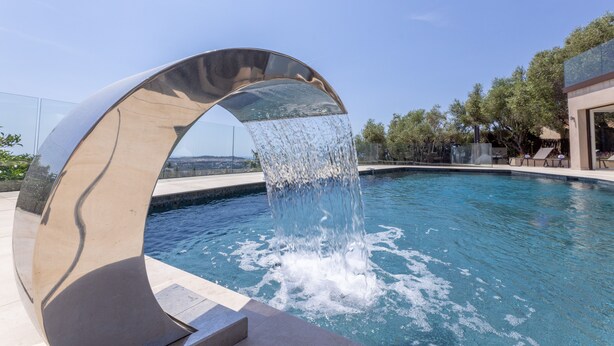 A modern pool with a metallic arch structure and water cascading down. - Luxury Villa for Rent Mougins (Mougins)