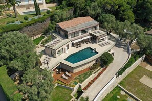 Ein modernes, zweistöckiges Haus mit Swimmingpool, Sitzgelegenheit im Freien und einem angelegten Garten.