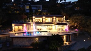 A modern two-story house with a swimming pool, outdoor seating, and a well-lit patio area. - Luxury Villa for Rent Mougins (Mougins)