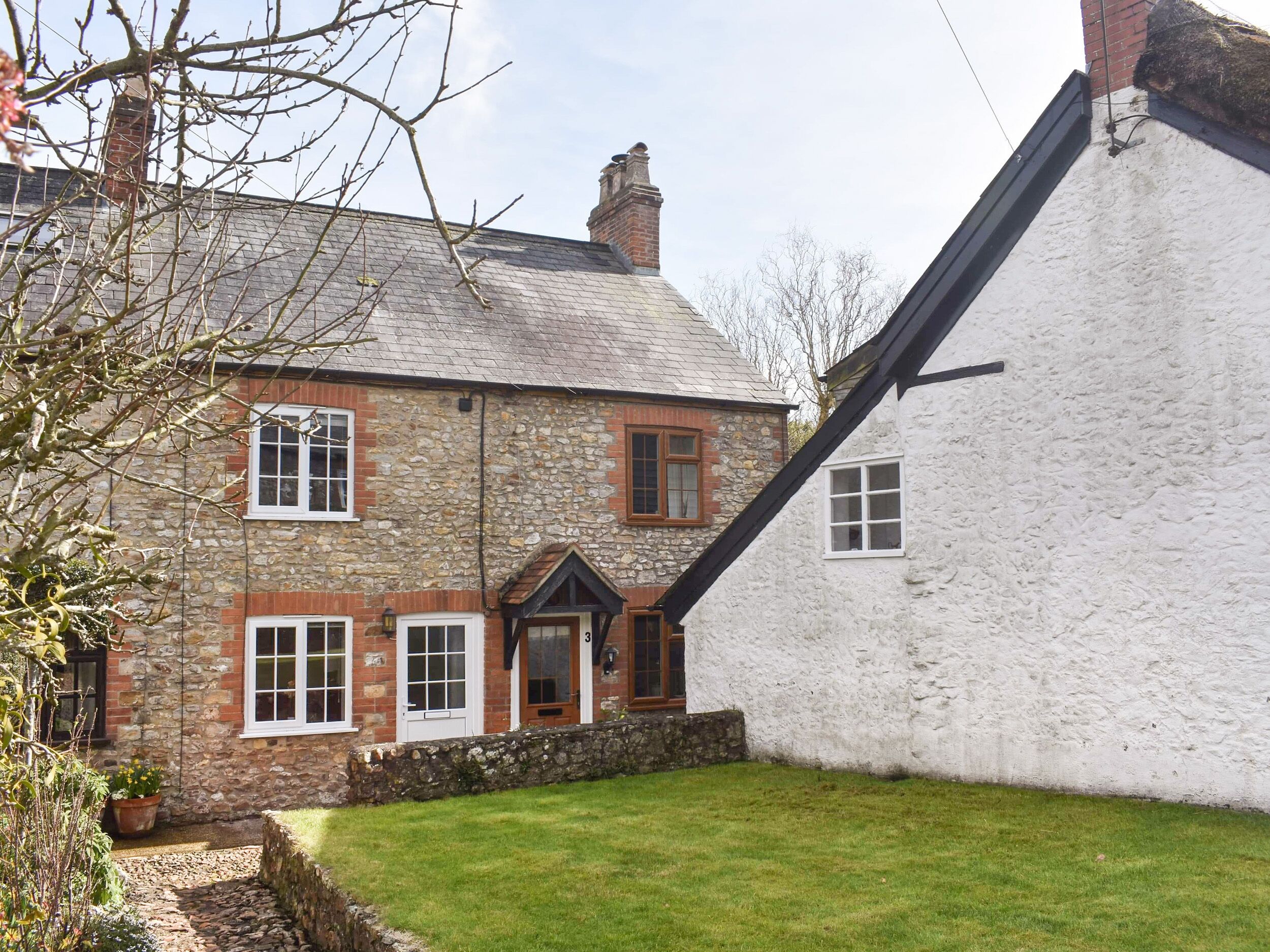 A traditional stone house with a sloped roof and a white exterior.
