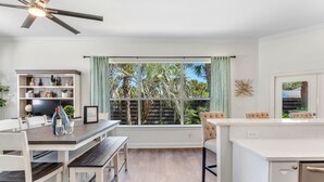 A modern kitchen with a dining area, large windows with curtains, and a ceiling fan. - Spacious Ocean Retreat~Minutes to the Beach, BBQ, Pool, Beach Gear, and More! (Destin)