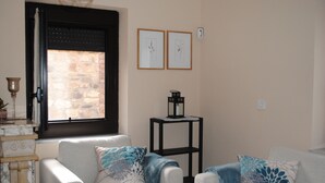 Een woonkamer met twee banken, een salontafel en een raam met uitzicht op een stenen muur.