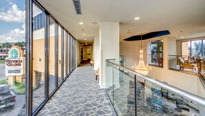 A modern hotel interior with a glass corridor, a chandelier, and a view of the ocean.