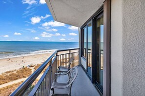 A balcony with a view of the beach and ocean.