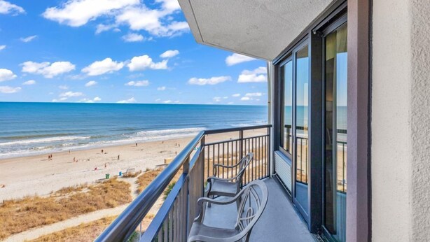 A balcony with a view of the beach and ocean.