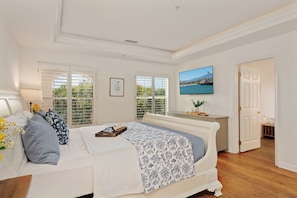 A bedroom with a bed, a bedside table, a TV, and a window with blinds.