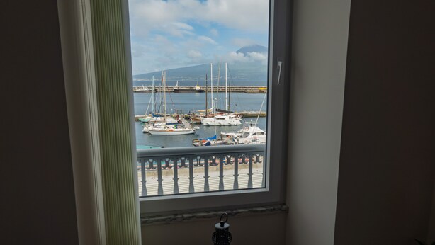 A view from a room with a window overlooking a marina with several boats docked. - Nereida (Horta)