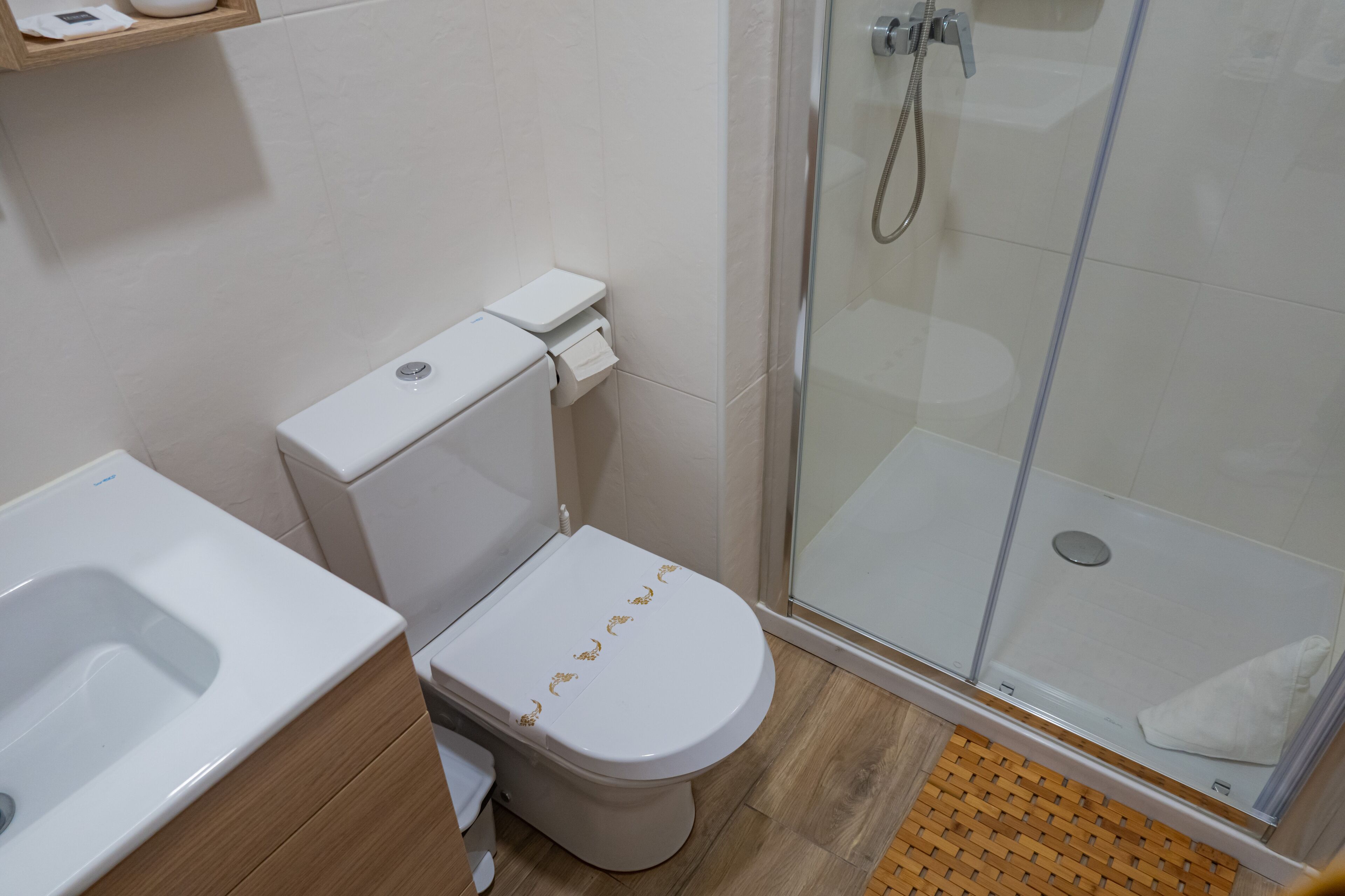 A bathroom with a toilet, a shower enclosure, and a sink.