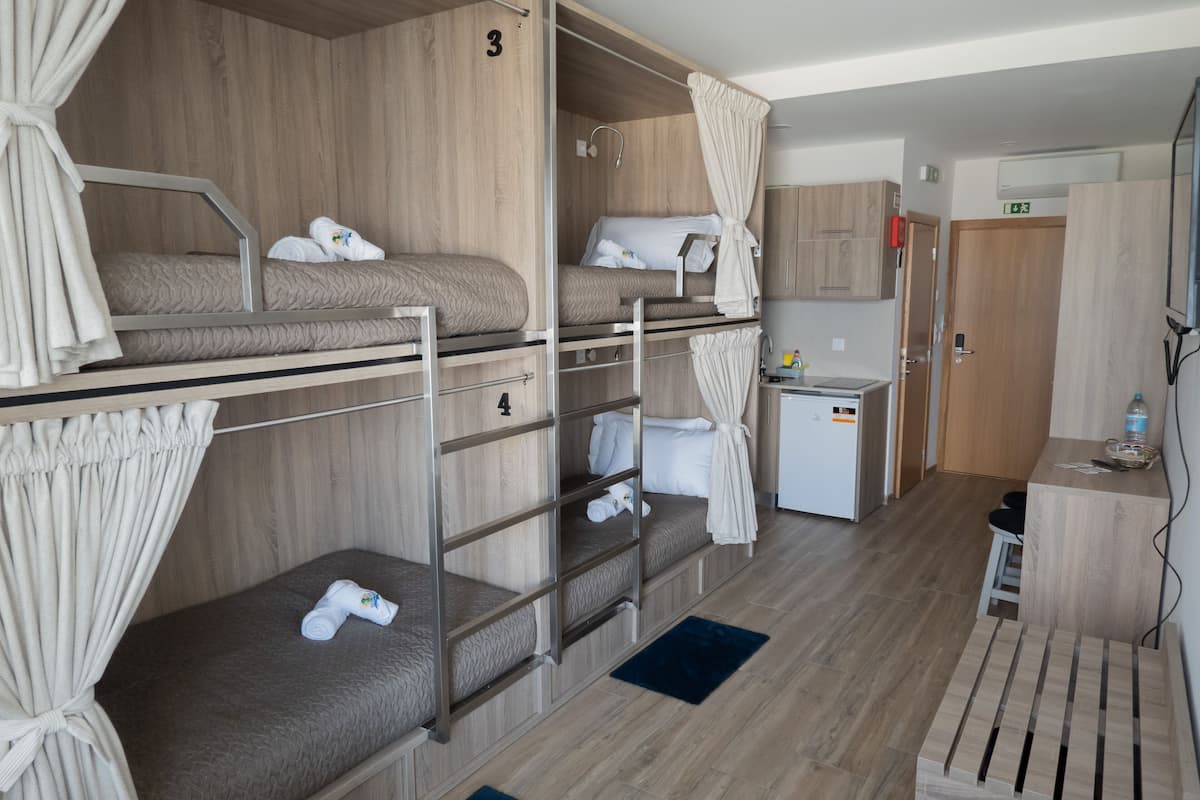 Habitación con literas, una kitchenette, una mesa pequeña y una puerta.