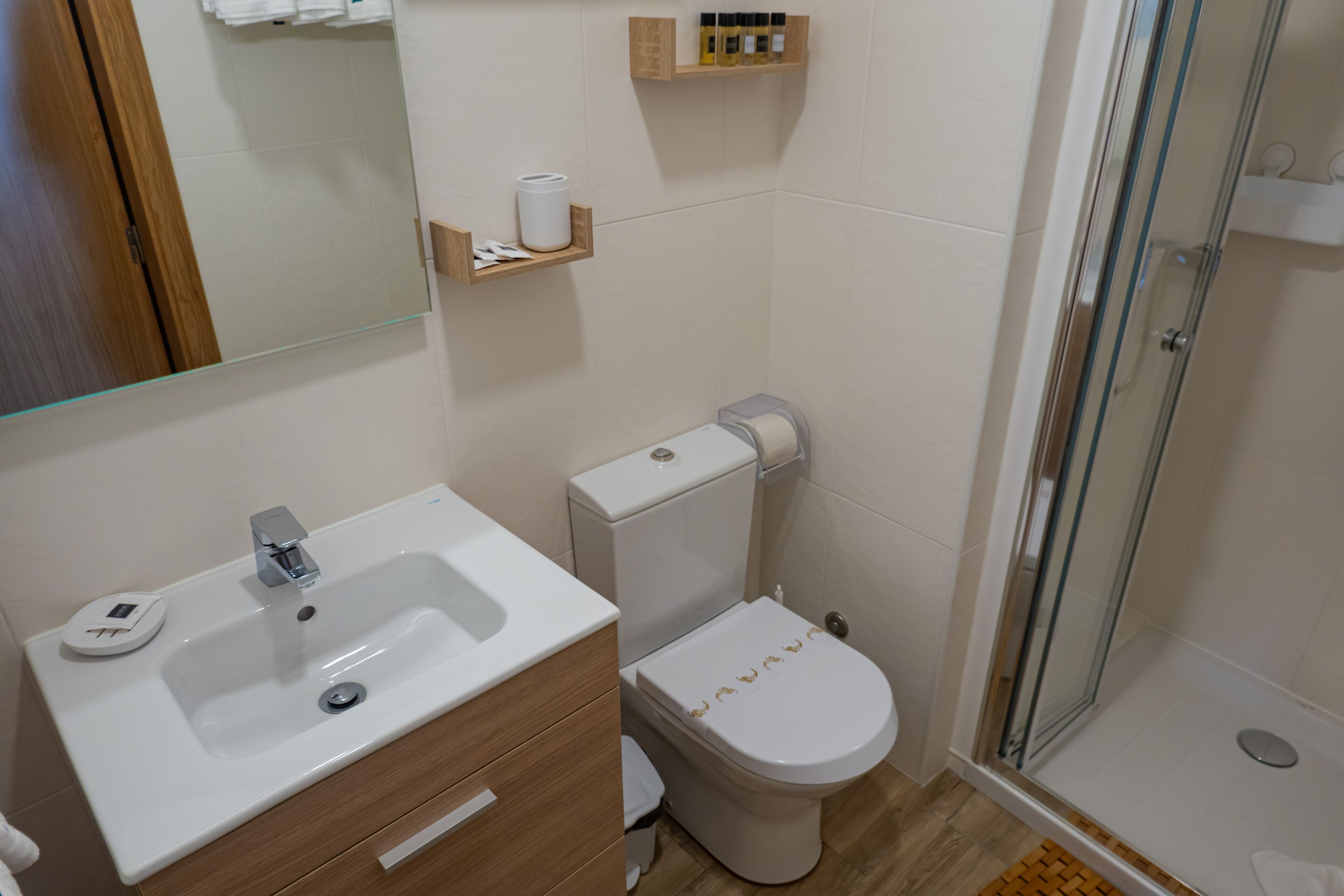 Een badkamer met een wastafel, toilet en een douchecabine met glazen wanden.