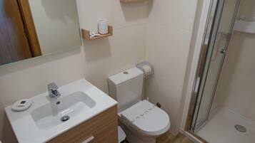 Een badkamer met een wastafel, toilet en een douchecabine met glazen wanden.