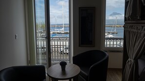A room with a view of a marina, a round table with a plant, and two chairs. - Nereida (Horta)