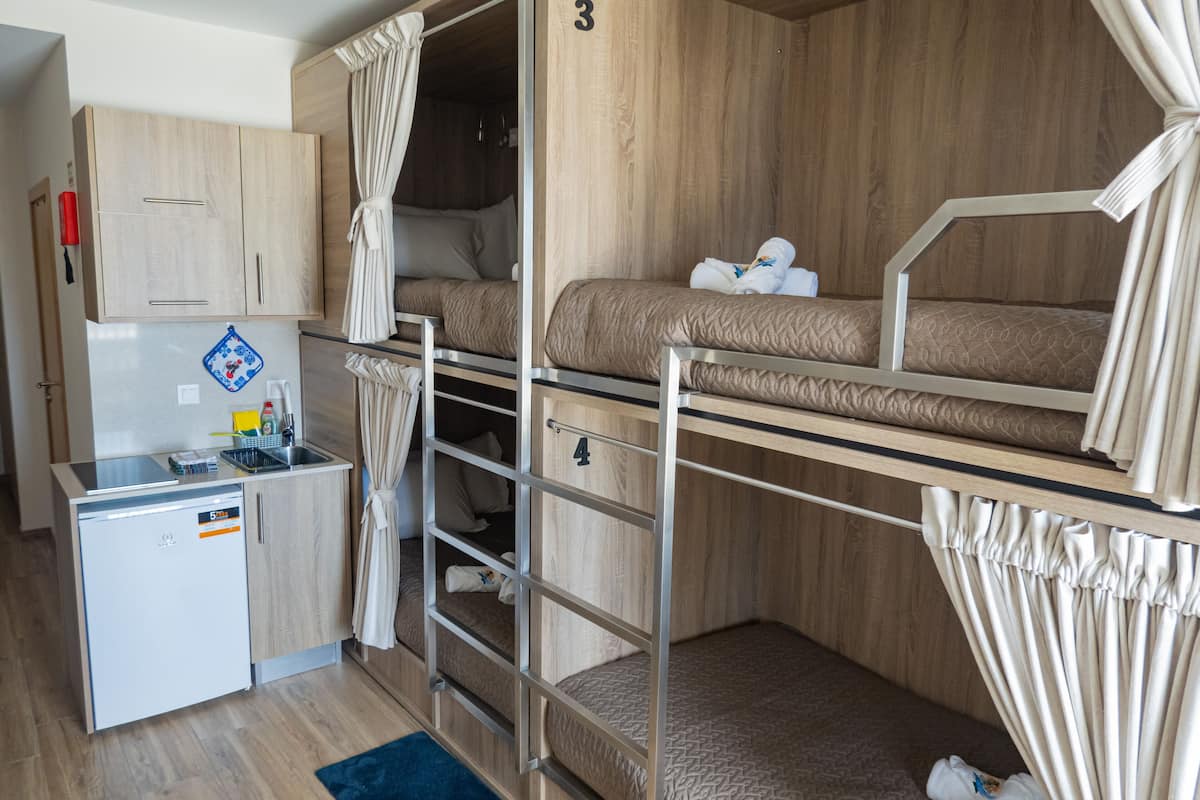 Una habitación pequeña con literas, una kitchenette compacta y un armario de madera.