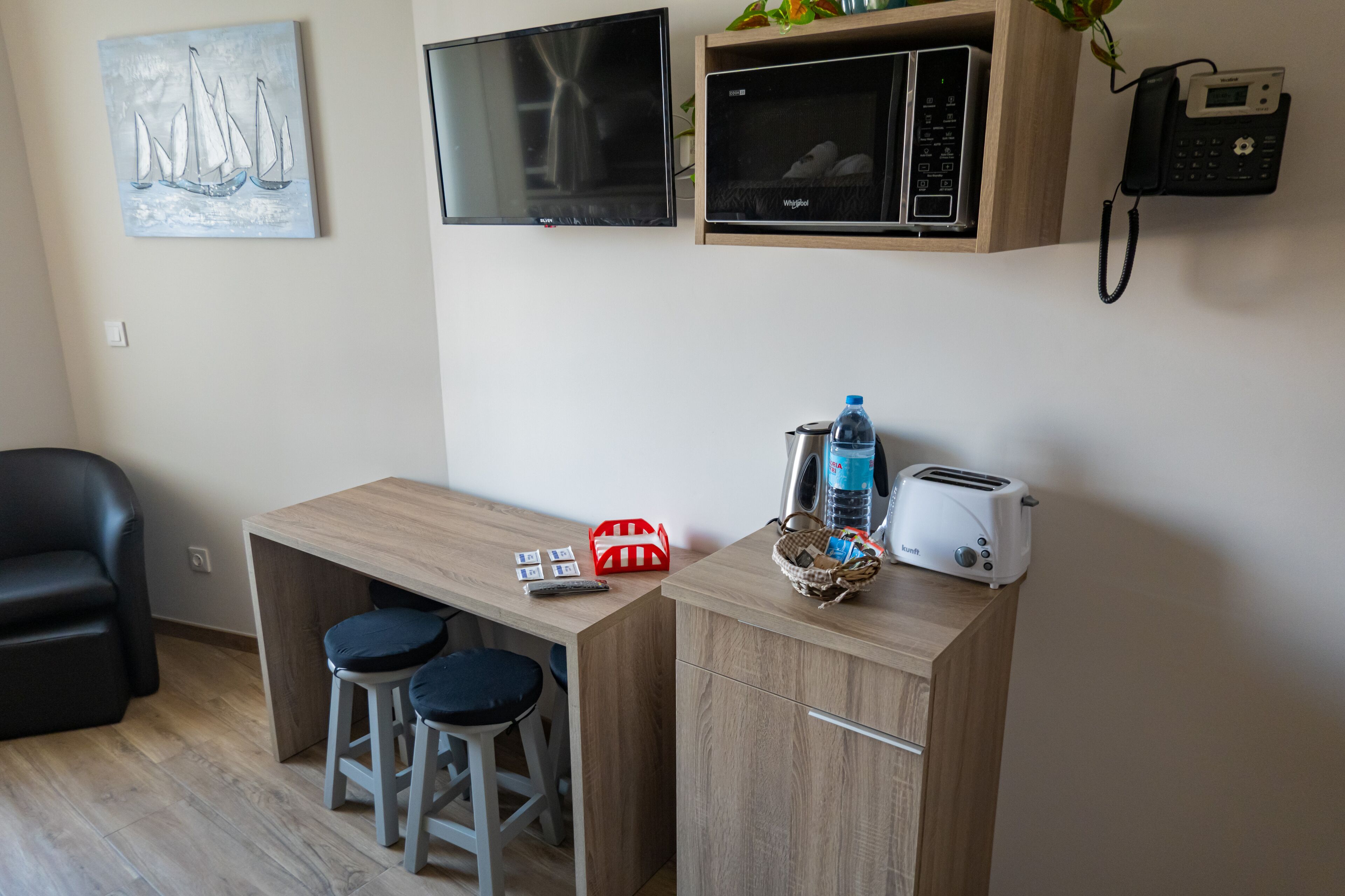 Une petite cuisine équipée d’un four à micro-ondes, d’un grille-pain et de quelques tabourets de bar.
