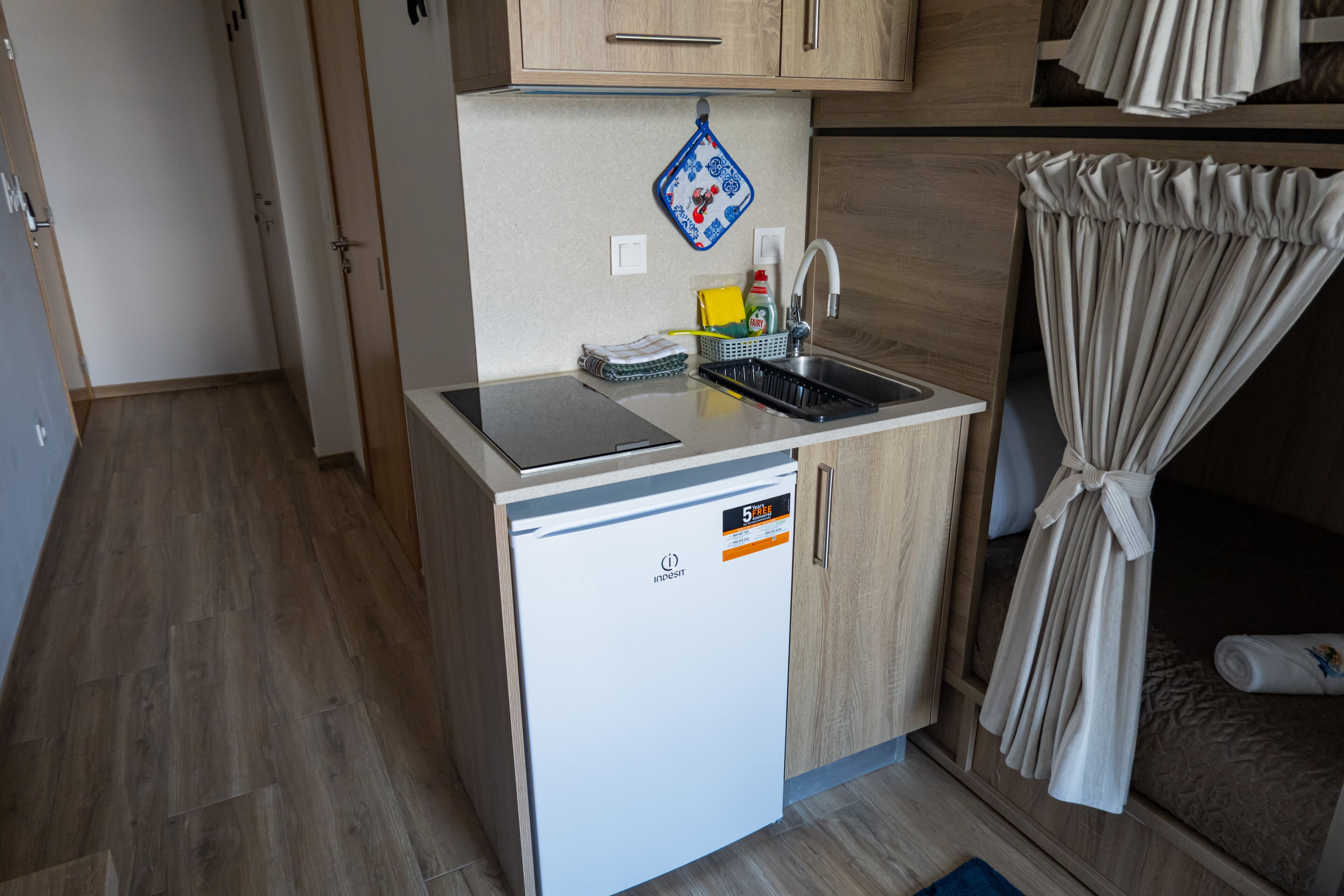Una kitchenette compacta con lavavajillas integrado, un fregadero y una pequeña encimera.