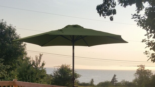 Une terrasse en bois, aménagée avec du mobilier d’extérieur, notamment des chaises et une table, donnant sur un jardin fleuri et délimité par une clôture.