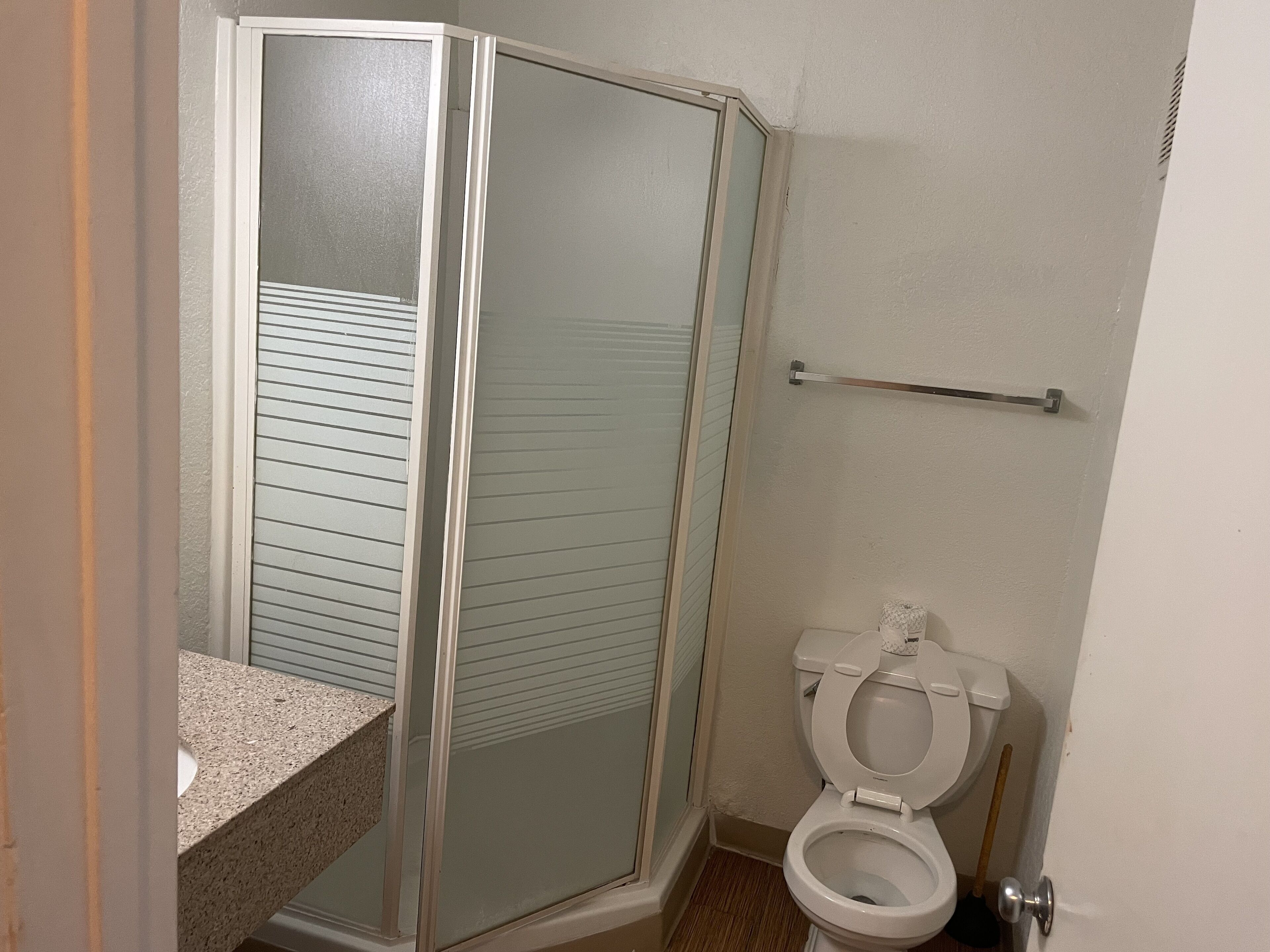 A bathroom with a shower enclosure, toilet, and a towel rack.