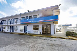 A motel with a 'WELCOME' sign, a covered parking area, and a visible room number 1051.