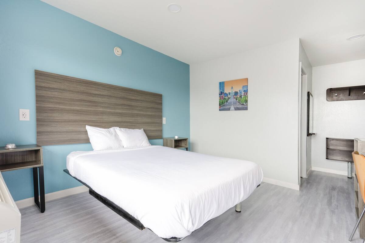Quarto de hotel moderno com uma cama grande, uma mesa e uma cadeira.