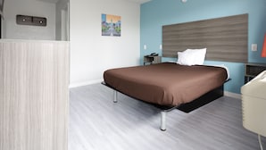 Una habitación de hotel moderna con cama, mesita de noche y un escritorio pequeño con silla.