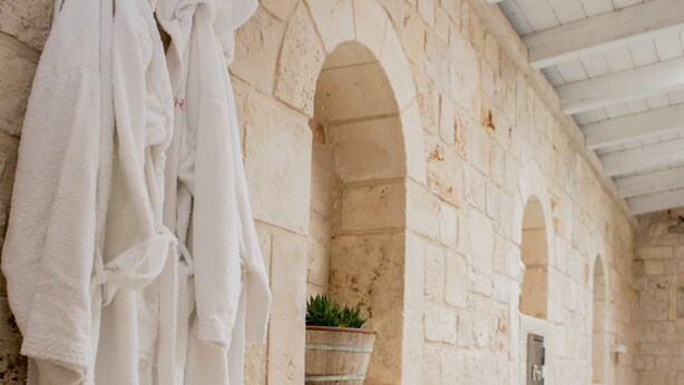 A stone-walled spa area with a pool, towels, and a potted plant.
