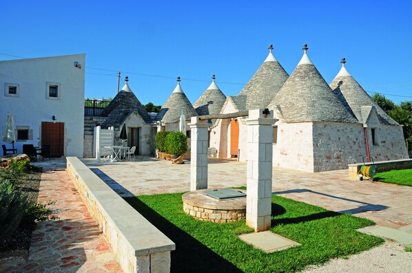 A courtyard with stone buildings, a white building, and a paved walkway.