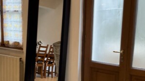 Ein Zimmer mit einem großen Spiegel, einer Holztür und einem Heizkörper.