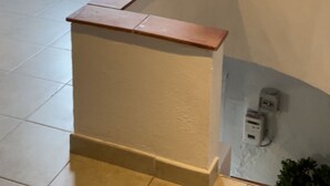 Eine Ecke eines Raumes mit weißer Wand, einer Holztür mit Milchglasfenstern und einem kleinen weißen Gegenstand an der Wand.
