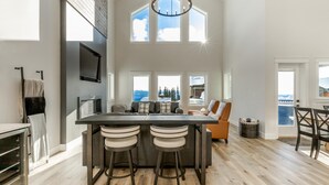 A spacious kitchen with a large island, bar stools, and a view of mountains through the windows.