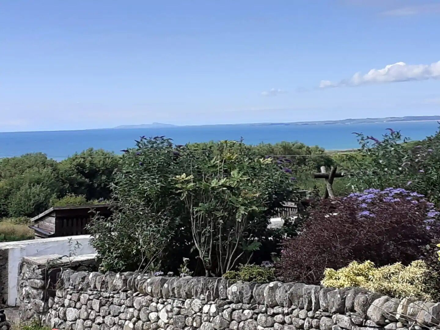 A stone wall with a view of the sea and distant mountains.