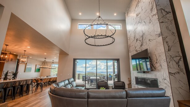 A spacious living area with a large sofa, a dining area with a long table, and a kitchen with modern lighting.