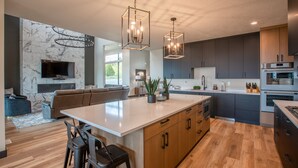 A modern kitchen with a large island, dark cabinets, and stainless steel appliances.
