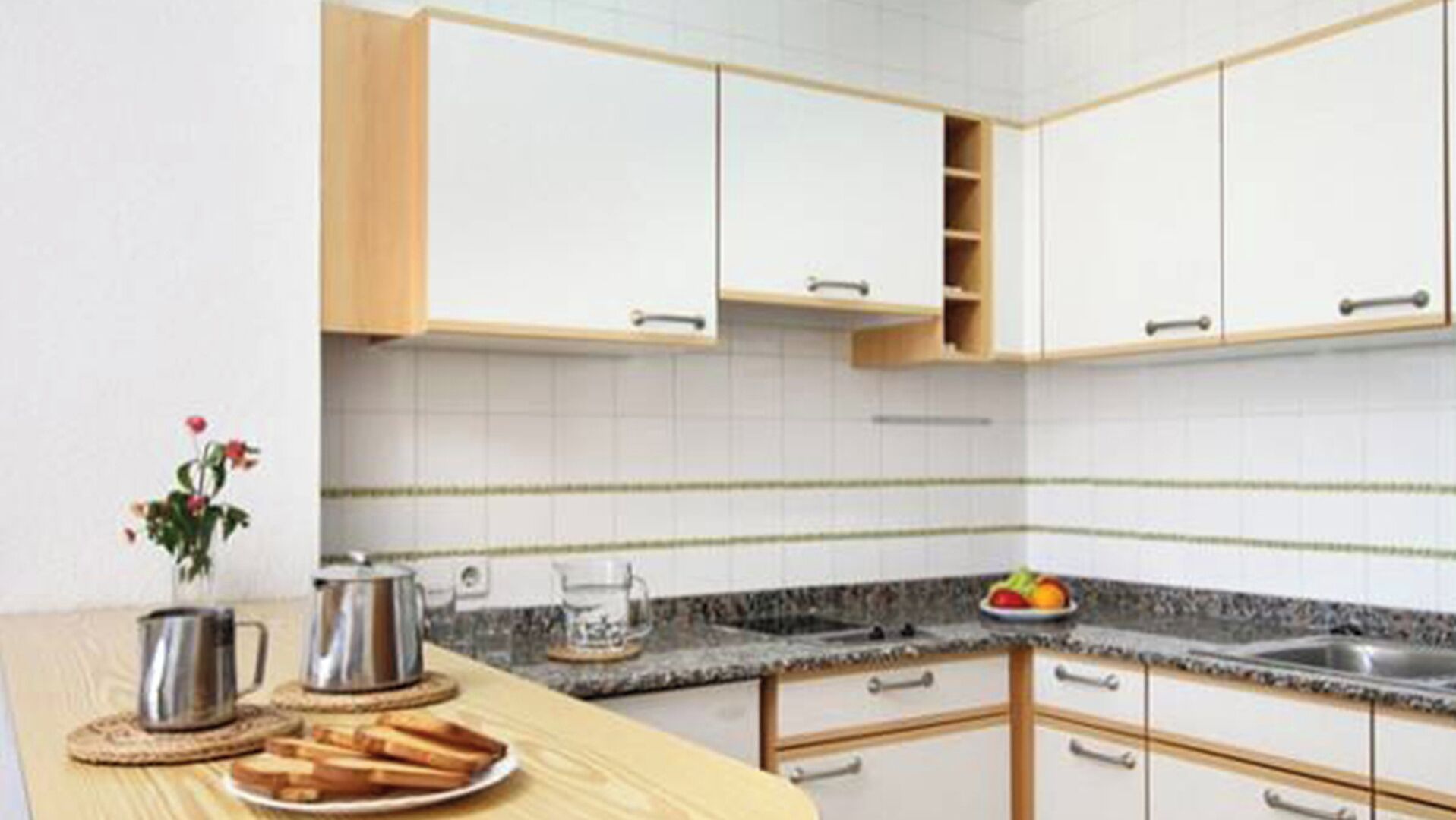 A modern kitchen with white cabinets, a granite countertop, and a small sink.