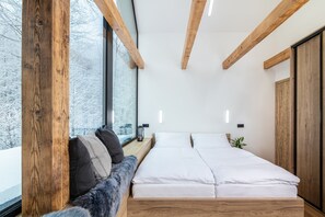 A modern bedroom with a wooden bed frame, a bench with cushions, a window with a view of trees, and a small plant on the bedside table. - Celadna Mcmh530 in Celadn (Celadna)