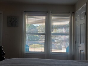 Ein Schlafzimmer mit Bett, Fenster mit Jalousien und Tür.