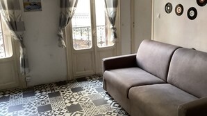 Una habitación con piso estampado, un sofá, cortinas y adornos de pared que incluyen discos de vinilo.
