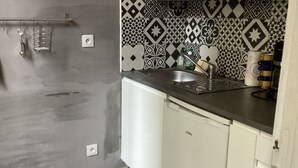 Una cocina con armarios blancos, encimera negra y azulejos decorativos en la pared.