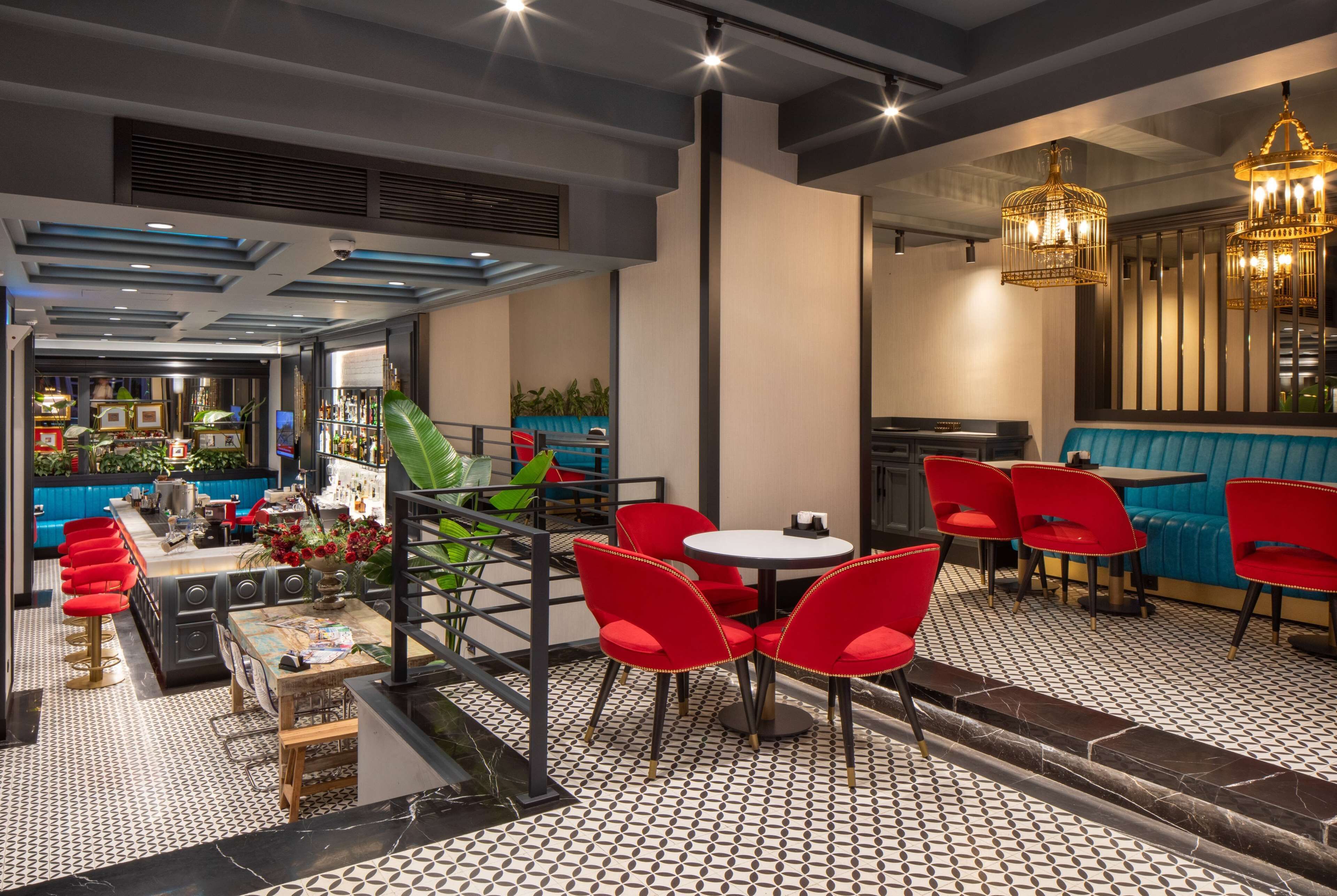 A restaurant with a bar area, red chairs, a blue booth, and a patterned floor.
