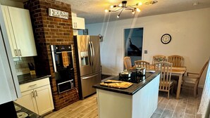 Una cocina moderna con una isla central, electrodomésticos de acero inoxidable y una pared de ladrillo decorativa.