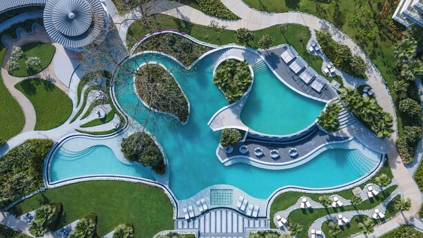 An aerial view of a resort with a large central pool, multiple smaller pools, and a winding pathway. - Aravali Marriott Resort & Spa, Delhi NCR (Faridabad)