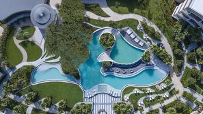 Ein Luftbild eines Resorts mit mehreren Schwimmbecken, angelegten Gärten und einer zentralen Wasserspule.