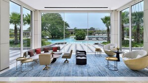 A spacious room with large windows, a pool view, and modern furniture. - Aravali Marriott Resort & Spa, Delhi NCR (Faridabad)