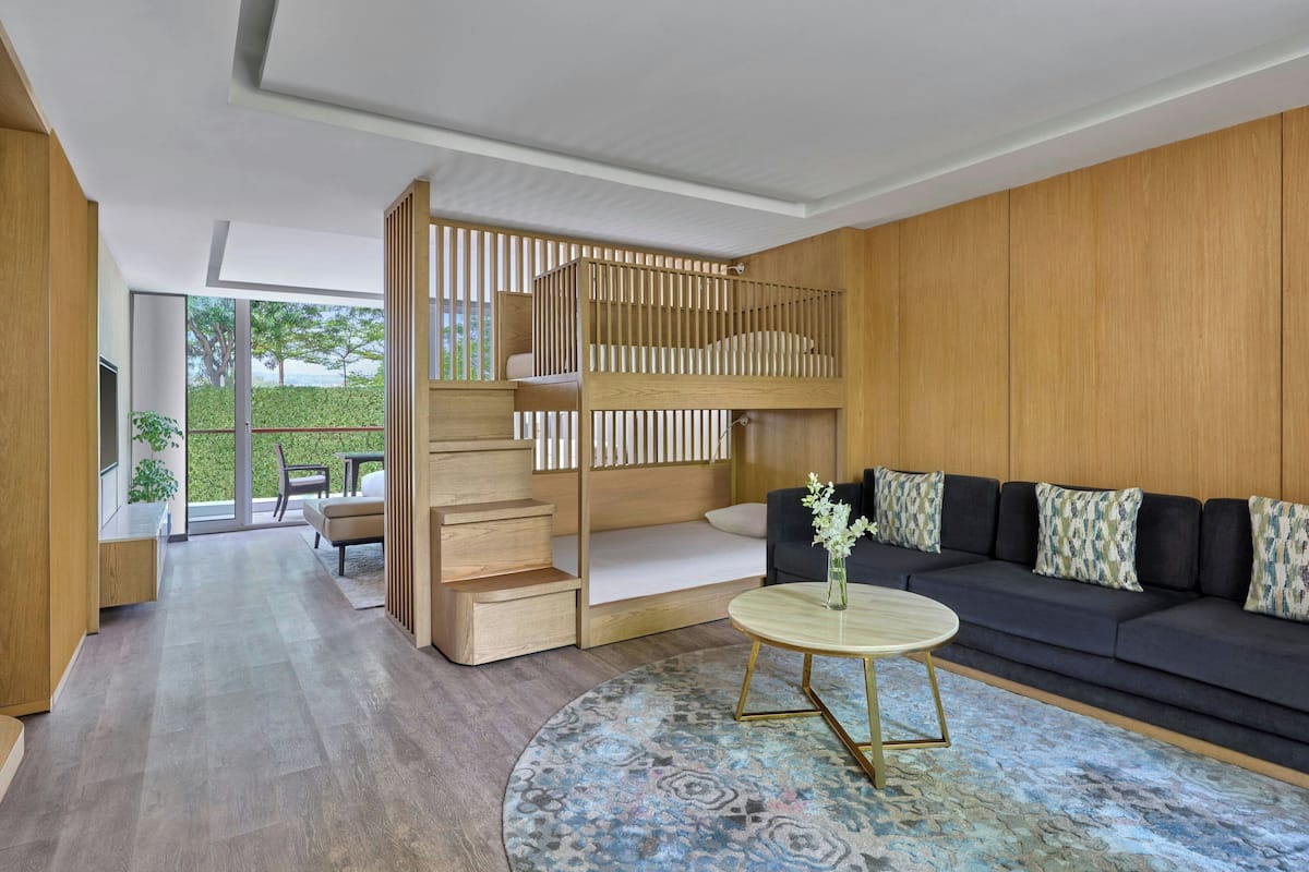 A modern living room with a bunk bed, a sofa, a coffee table, and a view of the outdoors.